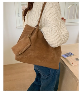 Détail d'un grand sac cabas en daim marron avec pochette latérale assortie et logo doré