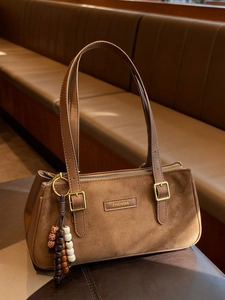 Borsa sottobraccio vintage in camoscio marrone da donna con ciondolo su panca in pelle