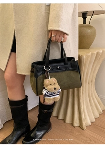 Dettaglio della borsa in pelle scamosciata verde oliva con inserti neri e ciondolo