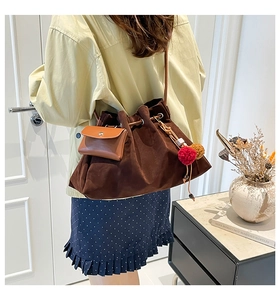 Macro detail of dark brown suede bucket bag with drawstring and colorful fur ball pendant