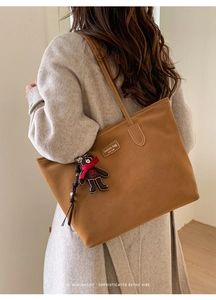 Detail of brown faux suede tote bag featuring a cute teddy bear charm and leather logo patch