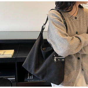 Detail of black suede hobo bag with silver rivets and eyelet shoulder strap