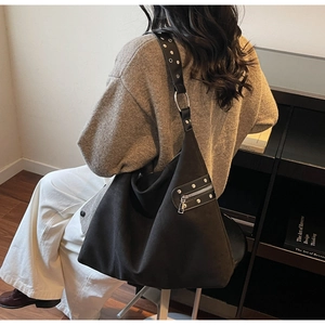 Detail of black large capacity shoulder bag with silver rivet straps and metal rings