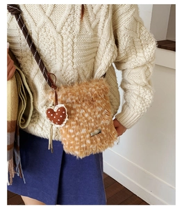 Nahaufnahme der flauschigen Umhängetasche mit Herzanhänger auf einem Strickpullover