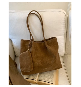 Close-up of retro brown matte tote bag with matching coin purse on a white sofa