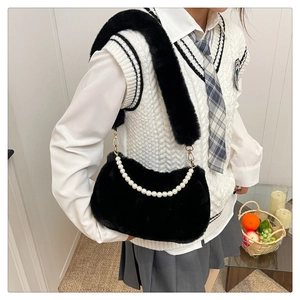 Détail d'un petit sac pelucheux noir avec chaîne en perles porté par un mannequin en intérieur