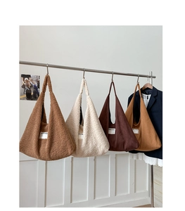 Close-up of fluffy faux fur and suede hobo bags with SEEYOU label on metal hangers