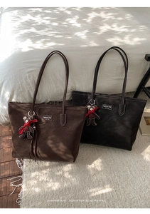 Detail of vintage suede tote bags in brown and black with bear charms and logo label