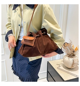Close-up of brown suede bucket bag featuring a drawstring closure and a small coin purse charm