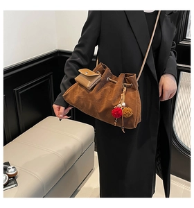 Detail of brown suede bucket bag with contrast fur pompom and mini pouch charm