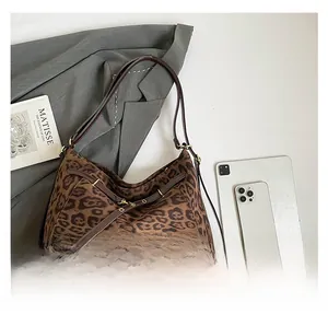 Detail of leopard print tote bag featuring brown leather handles and gold metal eyelets