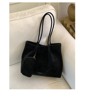 Close-up of black suede tote bag with contrast stitching and golden branding details