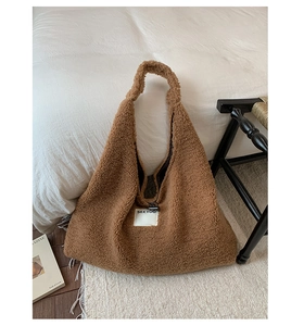 Detailed close-up of brown faux shearling tote bag with a minimalist white woven brand tag
