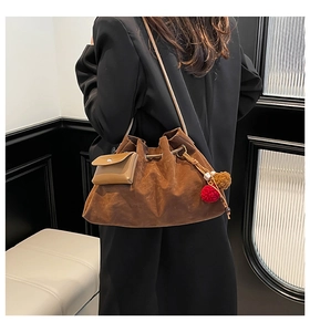 Brown faux suede hobo bag featuring tassel charm and mini envelope pouch on a model