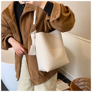 Detailed macro view of cream litchi texture leather tote bag with gold logo and strap