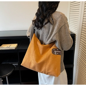 Detail of suede tote bag with side rivet zipper pocket and mustard yellow texture