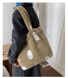 Dettaglio della borsa tote in peluche kaki con stampa orso indossata da una modella