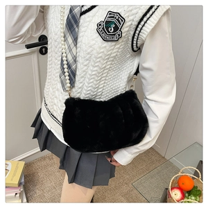 Détail d'un petit sac carré en fausse fourrure noire avec une longue bandoulière en perles