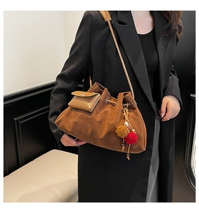 Detail of vintage brown suede bucket bag featuring drawstring closure and fuzzy pom-pom charm