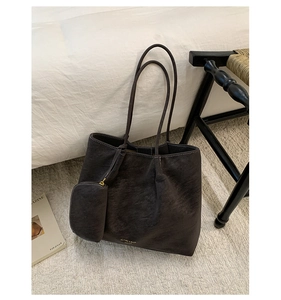 Détail d'un grand sac cabas rétro marron foncé avec petite pochette assortie sur tapis