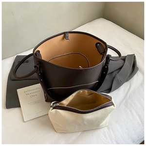 Top-down view of a dark brown leather bucket bag with a cream canvas inner pouch