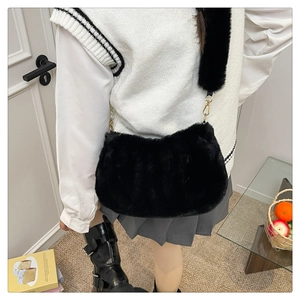 Détail d'un sac à bandoulière en fausse fourrure noire porté par un mannequin