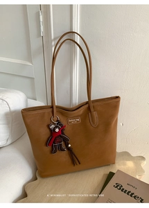 Detail of vintage brown suede tote bag with cute bear pendant and leather brand tag