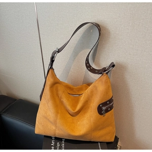 Close-up of mustard yellow suede hobo bag with brown leather strap and silver eyelets