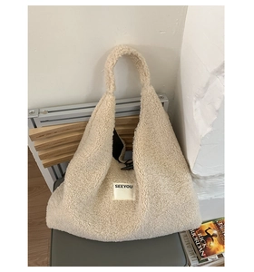 Detailed texture of beige faux shearling tote bag on a grey chair with label detail