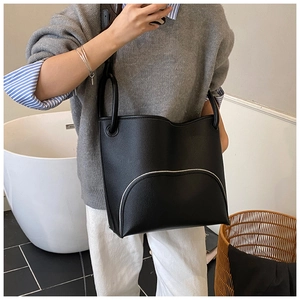 Detail of black lychee grain leather bucket bag with silver curved line accents