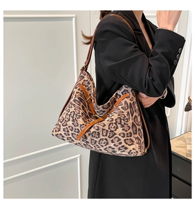 Detailed side view of leopard print tote bag with brown leather shoulder straps