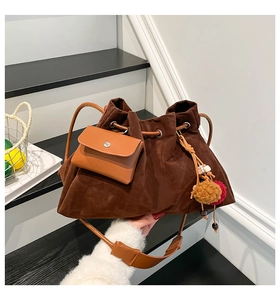 Detail of vintage brown suede bucket bag featuring drawstring closure and plush pendant