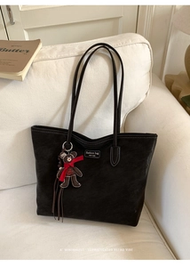 Black suede tote bag detail with white contrast stitching and a cute bear charm