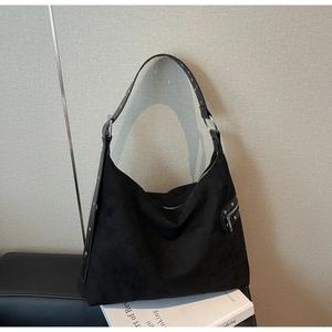 Detail of black suede hobo bag featuring metal zipper, rivets and wide strap buckles