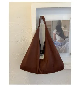 Detail of dark brown faux suede tote bag with minimalist metal buckle and woven logo tag