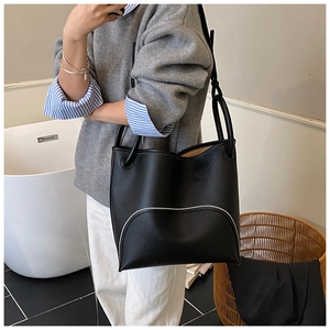 Detail of black lychee grain leather bucket bag with contrast white curved stitching