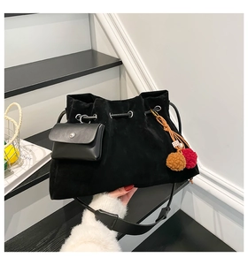 Detail of black faux suede drawstring bucket bag with mini purse and plush charms