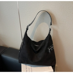 Detail of black suede hobo bag with silver zippers and rivet accents for daily commute
