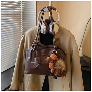 Dettaglio di una borsa tote in ecopelle marrone con ciondolo a cuore e cammello peluche