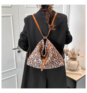 Detail of a triangular leopard print backpack with brown straps worn on a black blazer