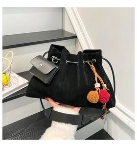 Detail view of black faux suede bucket bag with drawstring and decorative plush charm
