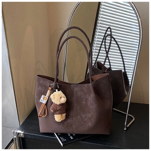 Close-up of vintage dark brown suede tote bag with a cute teddy bear charm detail
