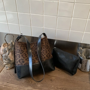 Detail view of leopard print tote bag with matching black inner pouch on a wooden surface