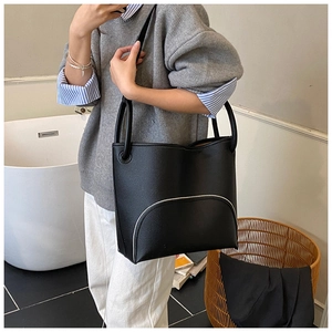 Close-up of black lychee grain leather bucket bag with white contrast piping pocket