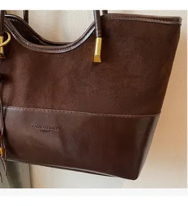 Detail shot of the contrast stitching and textures on the brown suede bucket bag