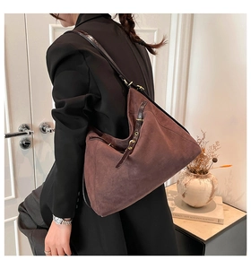 Close-up of a large dark brown matte suede tote bag with shiny leather straps and gold metal details