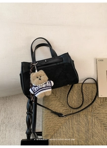Dettaglio della borsa Kelly nera in pelle martellata e camoscio con ciondolo a forma di orso
