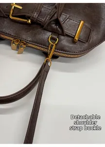 Detail of vintage brown leather bag showing gold hardware and detachable strap hook