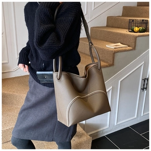 Close-up of khaki brown pebble leather bucket bag with curved stitching and strap