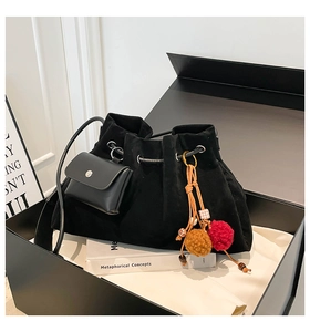 Detail of black suede drawstring bucket bag with mini purse and tassel in a gift box